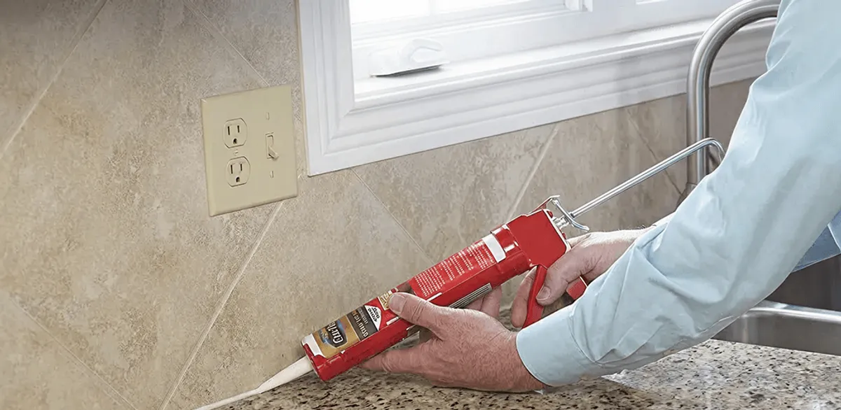 Handyman applying caulk along a kitchen backsplash and countertop seam in Savannah, GA